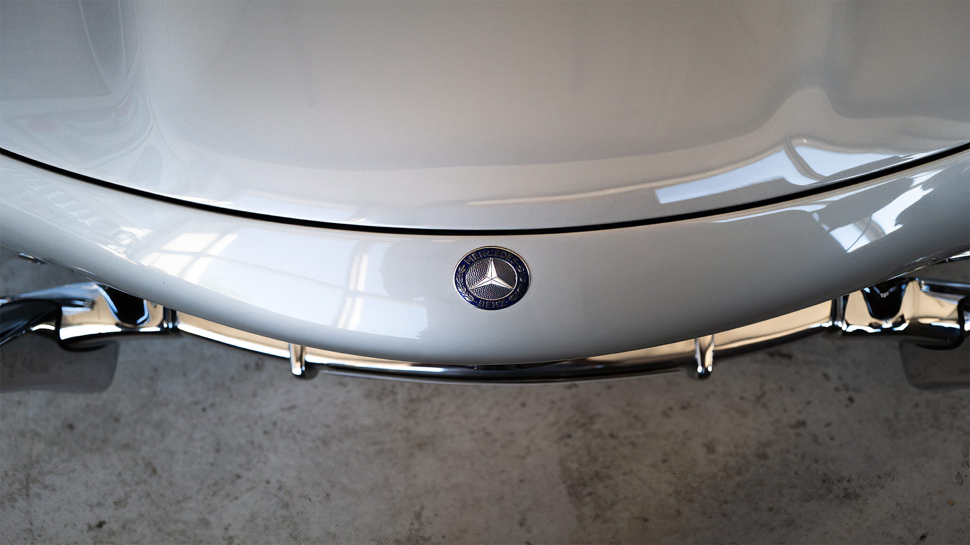 Silberne Motorhaube eines klassischen Mercedes mit Stern und Chromstoßstange